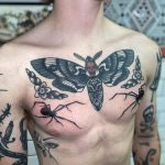 A man with a full bodysuit of traditional black work tattoos. Deadhead moth and spiders. Tattooed by Mike Wall at Cult Classic Tattoo