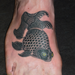 A black goldfish tattooed on a man's foot in a japanese style by Aaron Hewitt in Romford, Essex.